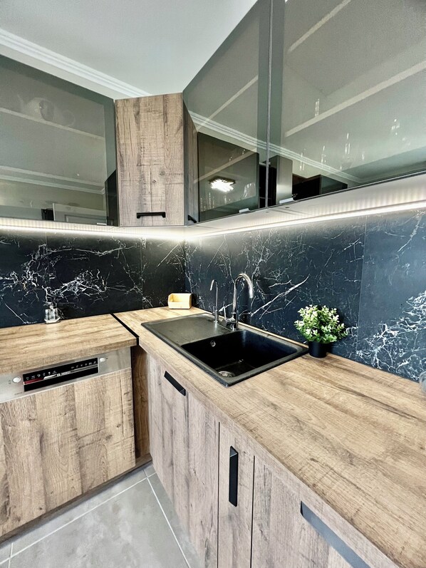 A modern kitchen with a black marble backsplash, wooden cabinetry, and a built-in sink. - Apparemment Moderne (Strasbourg)