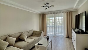 A modern living room with a beige sofa, a white coffee table, and a TV.