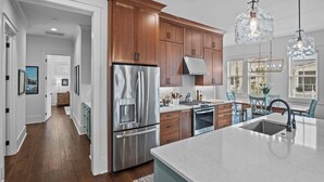 Una cocina moderna con electrodomésticos de acero inoxidable, armarios de madera y una isla grande con pileta.
