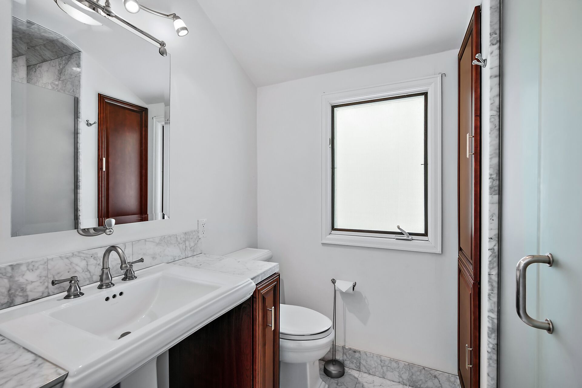 Ein Badezimmer mit Waschbecken, Spiegel, Toilette und Fenster.