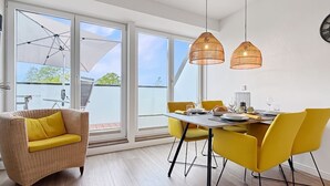 A dining area with a table, chairs, and a wicker sofa. - 3002 - Grömitz - Wohnung 3002 am Schoor in Grömitz (Grömitz)