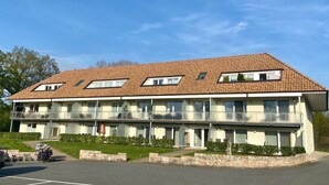 A multi-story hotel with a tiled roof, balconies, and a parking area. - 3002 - Grömitz - Wohnung 3002 am Schoor in Grömitz (Grömitz)