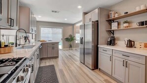 Une cuisine moderne dotée d’appareils électroménagers en acier inoxydable, de meubles de rangement en bois clair et d’un îlot central.