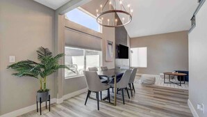 Un espace repas moderne avec une table ronde, des chaises, une plante en pot et un lustre.