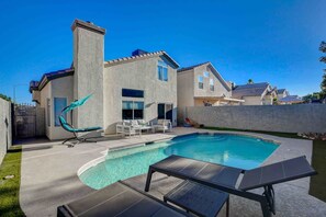 Una casa moderna con piscina, mobiliario exterior y un césped cuidado.