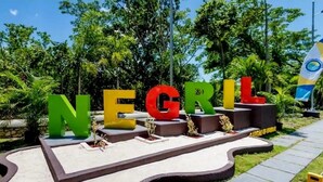 Un espace aménagé avec de grandes lettres colorées formant le mot « NEGRIL » sur une plateforme surélevée.
