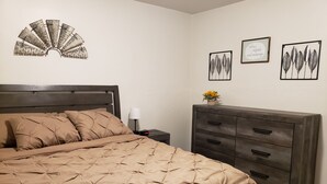 Ein Schlafzimmer mit Bett, Nachttisch, Kommode und Wandbildern.
