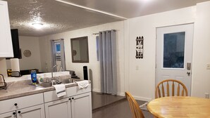 Eine kleine Küche mit Spüle, Arbeitsfläche und einem Holzespeisetisch mit Stühlen.