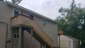 Ein zweistöckiges Haus mit einer Holztreppe, die zu einem Balkon führt.