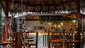 A restaurant with wooden tables and chairs, a bar area, and hanging plants. - Villa Éden  (Santarém)