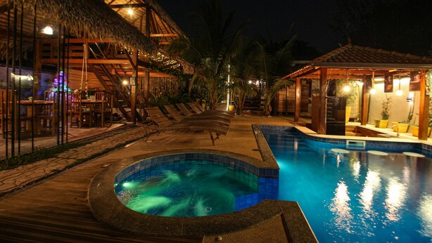 A pool area with a hot tub, lounge chairs, and a thatched-roof structure. - Villa Éden  (Santarém)