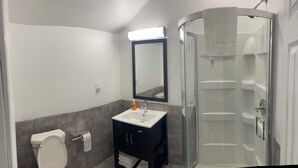 Une salle de bain moderne équipée de toilettes, d’un lavabo, d’un miroir et d’une douche à parois de verre.