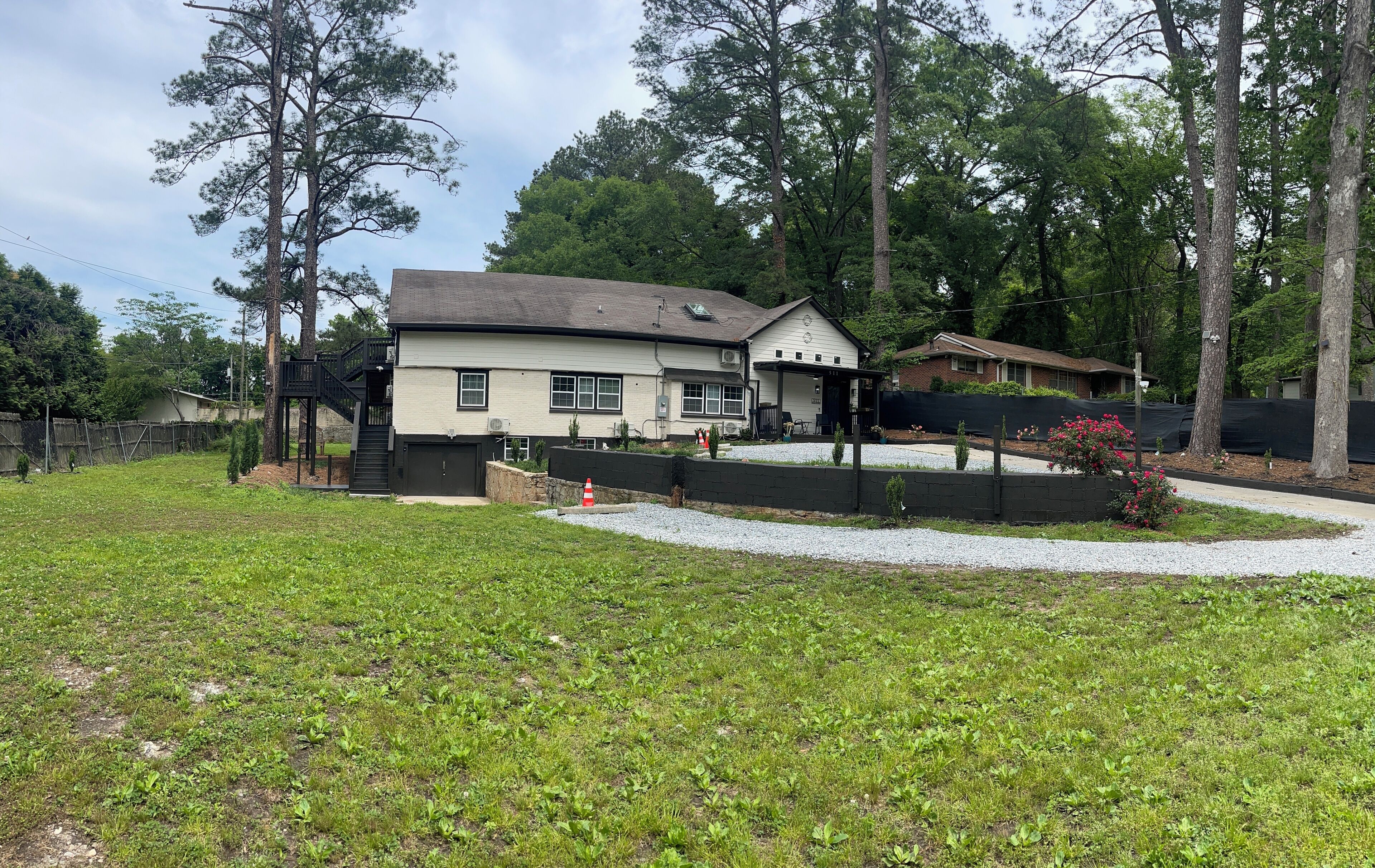 Een huis met twee verdiepingen, een overdekte veranda, een omheinde tuin en een grindpad.