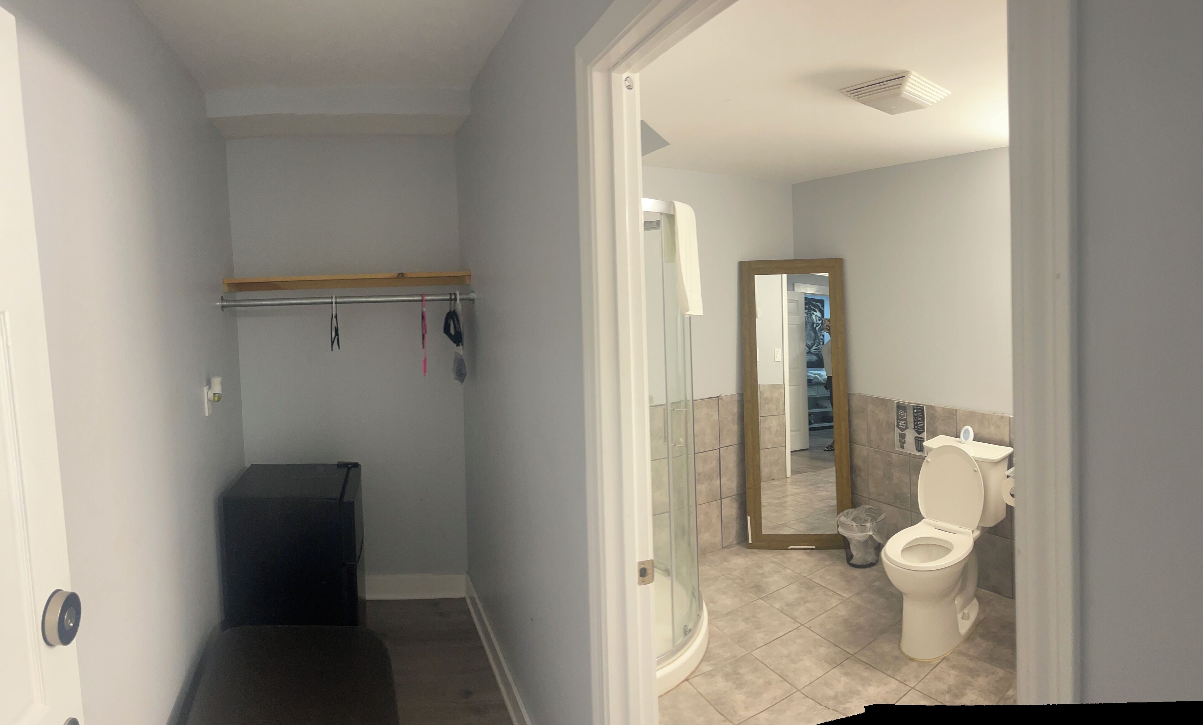 A bathroom with a shower, toilet, and a mirror.