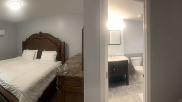 A bedroom with a bed, a vanity, and a bathroom with a toilet and sink.