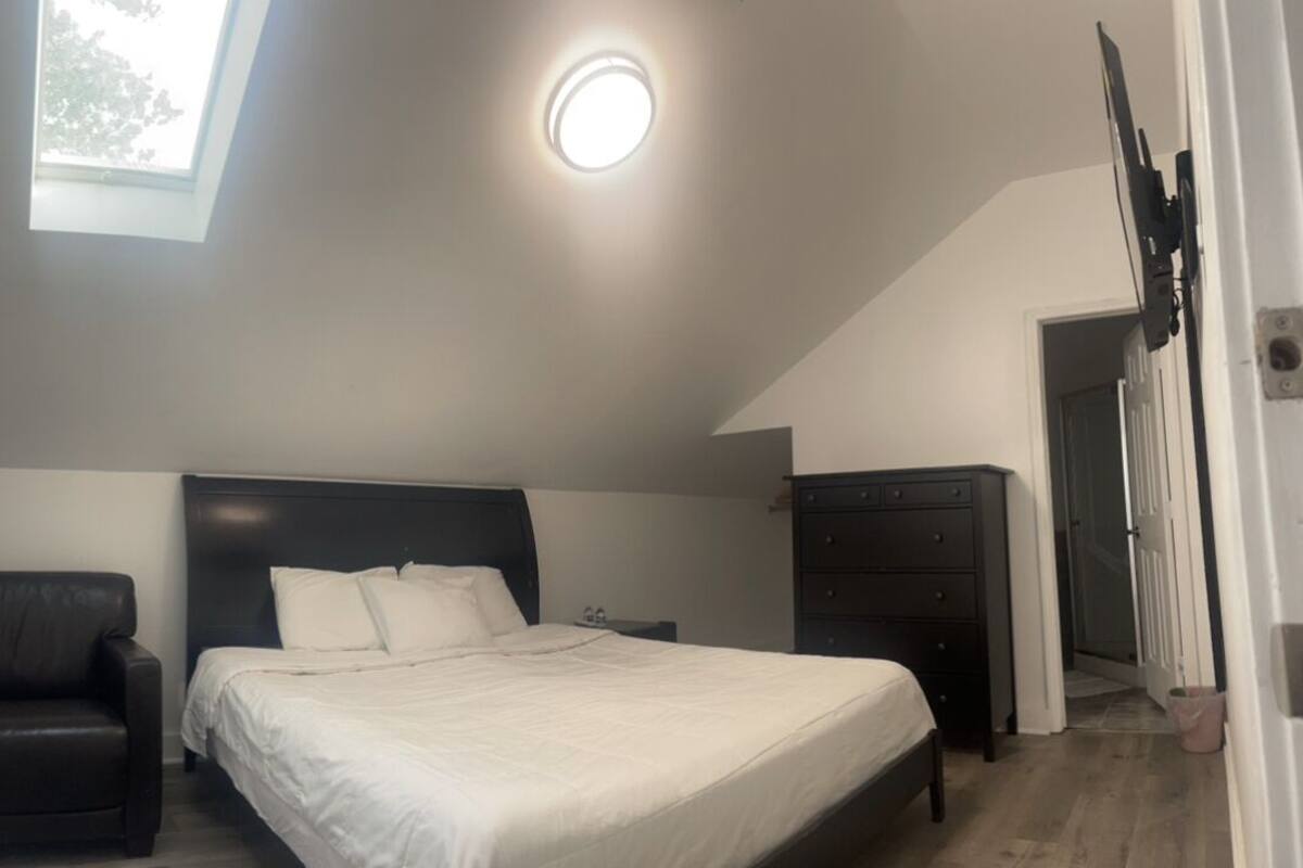 Une chambre à coucher avec un lit, une chaise, une commode et une lucarne.