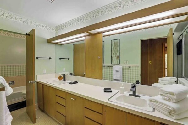 A bathroom with a double sink, wooden cabinets, a large mirror, and a towel rack.