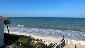 A beach view with a clear sky, a sandy shore, and a white fence. - 1/1 Ocean View Condo at Sandpiper. Watch rocket launches from the balcony! (Satellite Beach)