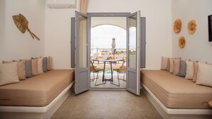 Une chambre avec un lit, une table et des chaises, et une vue sur la mer.