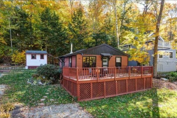 Escape to a serene cabin surrounded by a dense forest, featuring a cozy deck and a simple, functional design.
