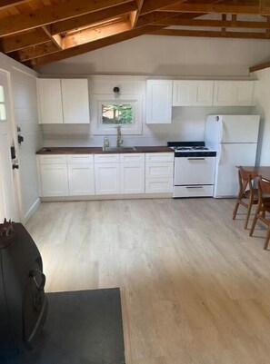 Compact kitchen with stove, refrigerator, and dining area.