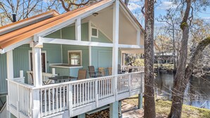 A two-story house with a covered porch and a view of a lake.