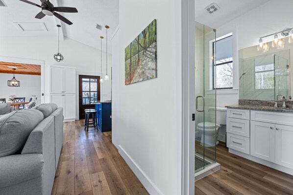 A modern kitchen with white cabinets, a granite countertop, and a glass shower enclosure.