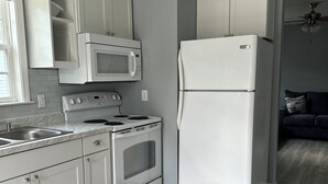 Een moderne keuken met witte apparaten, grijze wanden en een houten vloer.