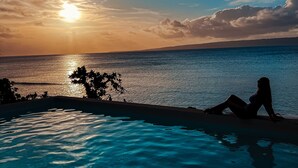 Ein Pool mit Blick auf den Ozean bei Sonnenuntergang.