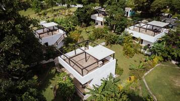Een modern resort met meerdere witte gebouwen, omgeven door weelderige begroeiing en palmbomen.