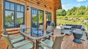 A wooden cabin with a glass-enclosed patio featuring wicker furniture and a glass table. - Eagle's Nest CITQ 271666 (Mont-Blanc)