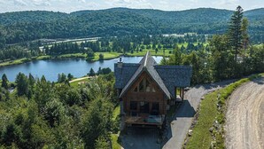 A cabin with a sloped roof, surrounded by a lake and forested hills. - Eagle's Nest CITQ 271666 (Mont-Blanc)