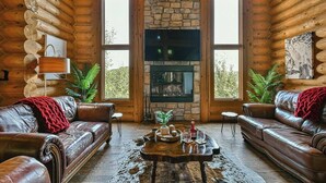 A log cabin interior with a stone fireplace, leather sofas, and large windows. - Eagle's Nest CITQ 271666 (Mont-Blanc)