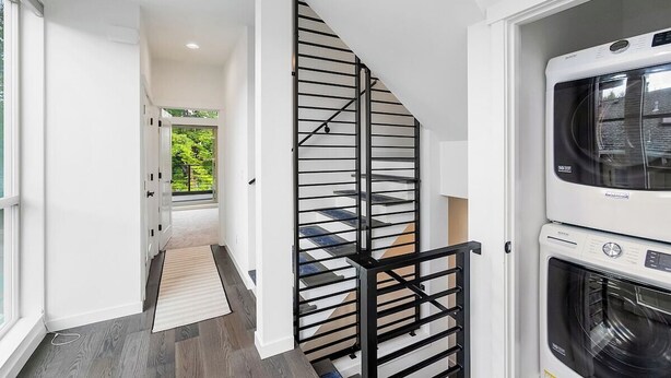 Un intérieur moderne avec un escalier, un lave-linge et une vue sur la verdure.