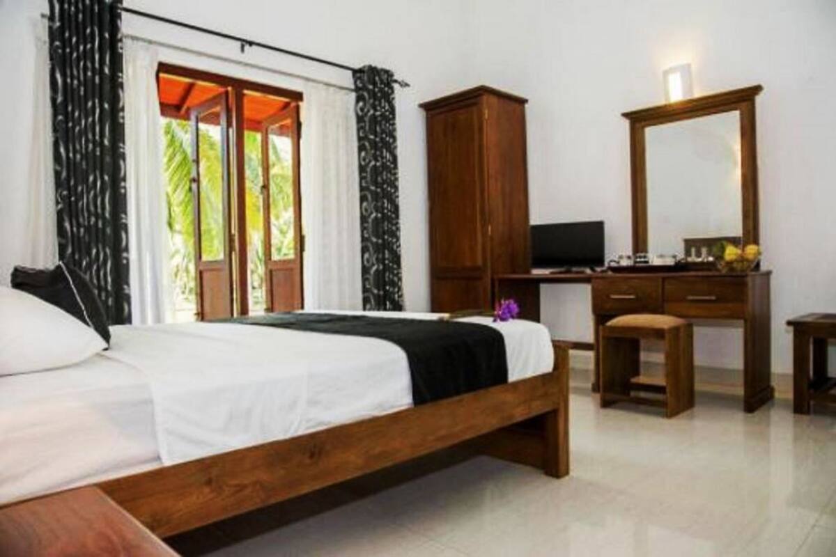 A bedroom with a wooden bed, a desk with a television, and a large mirror.