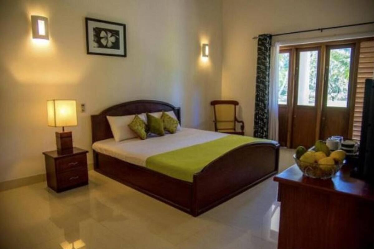 A bedroom with a bed, bedside table, lamp, and a window with curtains.