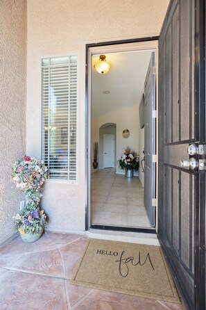 Welcome to a clean and inviting entrance, featuring a large door, doormat, and a potted plant.