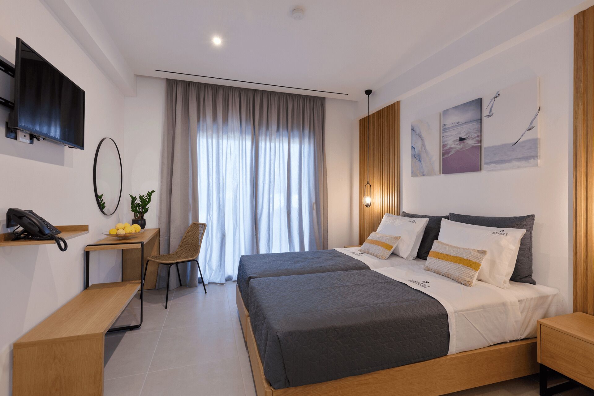 A modern hotel room with a large bed, a desk with a telephone, and a chair.