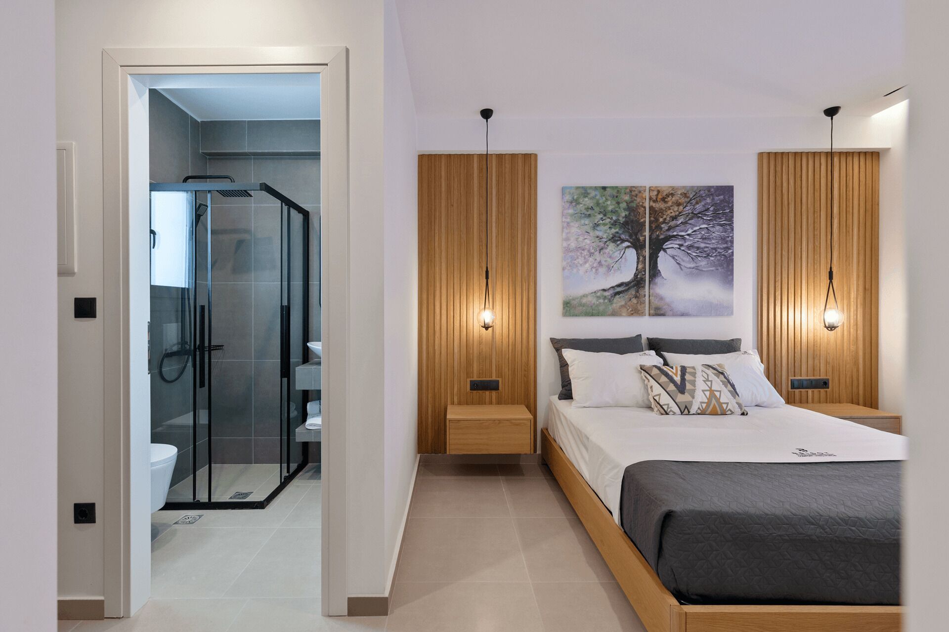 Une chambre moderne avec une douche en verre, un lambris en bois, un grand lit avec de nombreux oreillers et deux lampes fixées au mur.