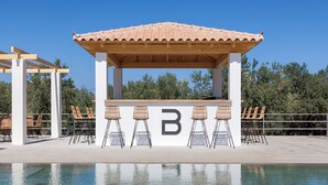 Un bar junto a la piscina con techo de azulejos y pilares blancos, rodeado de sillones de descanso.