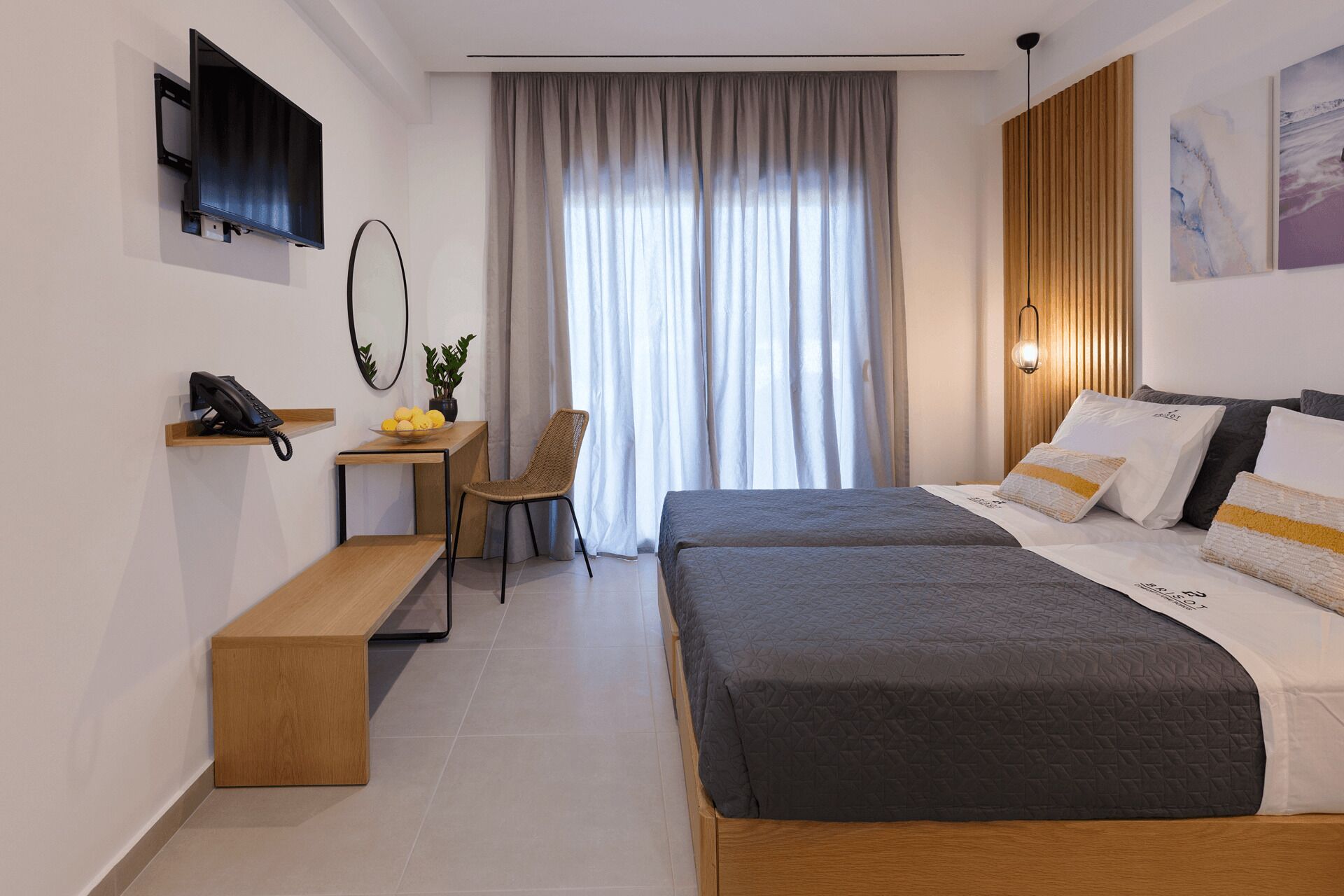 Una habitación de hotel moderna con cama, escritorio, silla, teléfono y ventana con cortinas.