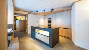 Una cocina moderna con una isla central, horno empotrado y una pared de acento de piedra.