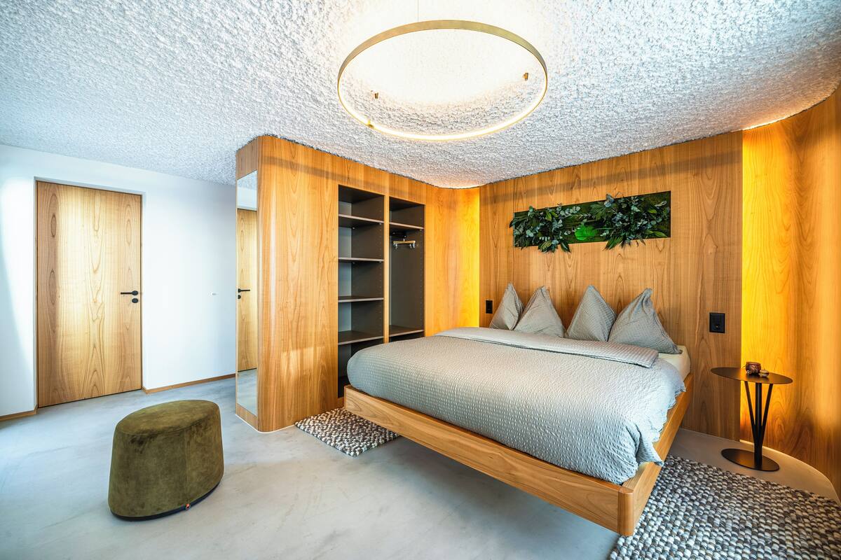 Ein modernes Schlafzimmer mit einem schwebenden Bett, Holzwänden und einer Deckenleuchte.