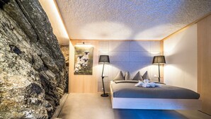 Un dormitorio con una cama, dos lámparas de noche, una obra de arte en la pared y un cabecero de madera.