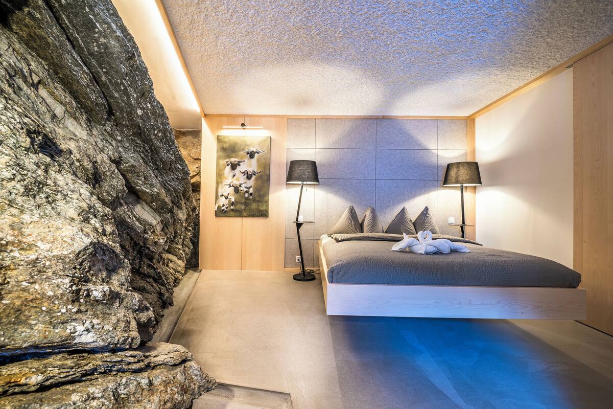 Ein Schlafzimmer mit einem Bett, zwei Nachttischlampen, einem Wandbild und einem Holz-Kopfteil.