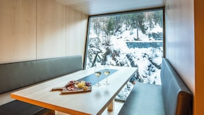 Un comedor moderno con una mesa de madera y un banco, una copa de vino y un plato de comida.