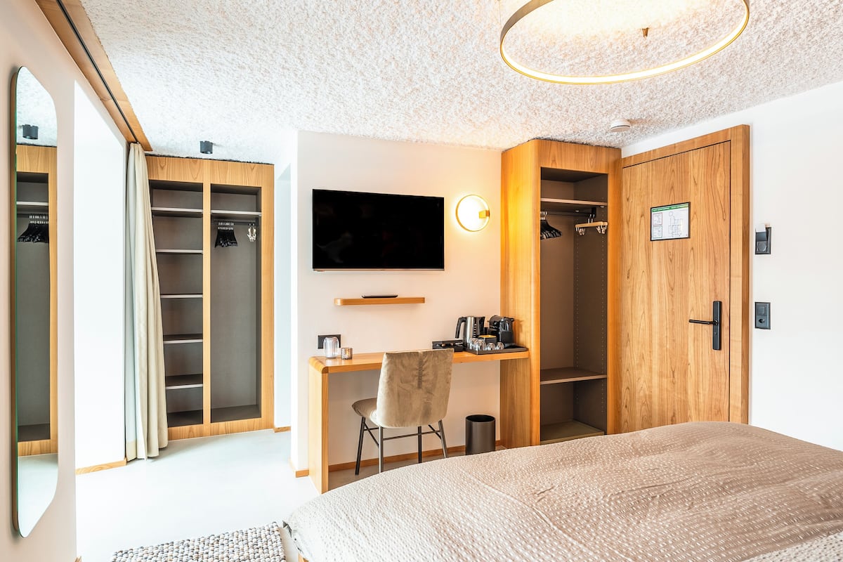 Ein Schlafzimmer mit einem großen Bett, einem Schreibtisch mit Stuhl, einem Fernseher und einem Kleiderschrank.