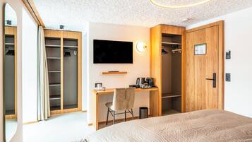 Ein Schlafzimmer mit einem großen Bett, einem Schreibtisch mit Stuhl, einem Fernseher und einem Kleiderschrank.
