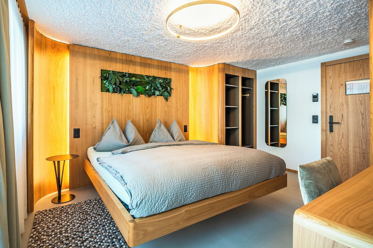 Ein modernes Schlafzimmer mit schwebendem Bett, Holzvertäfelung, eingebautem Kleiderschrank und einem kleinen Nachttisch.