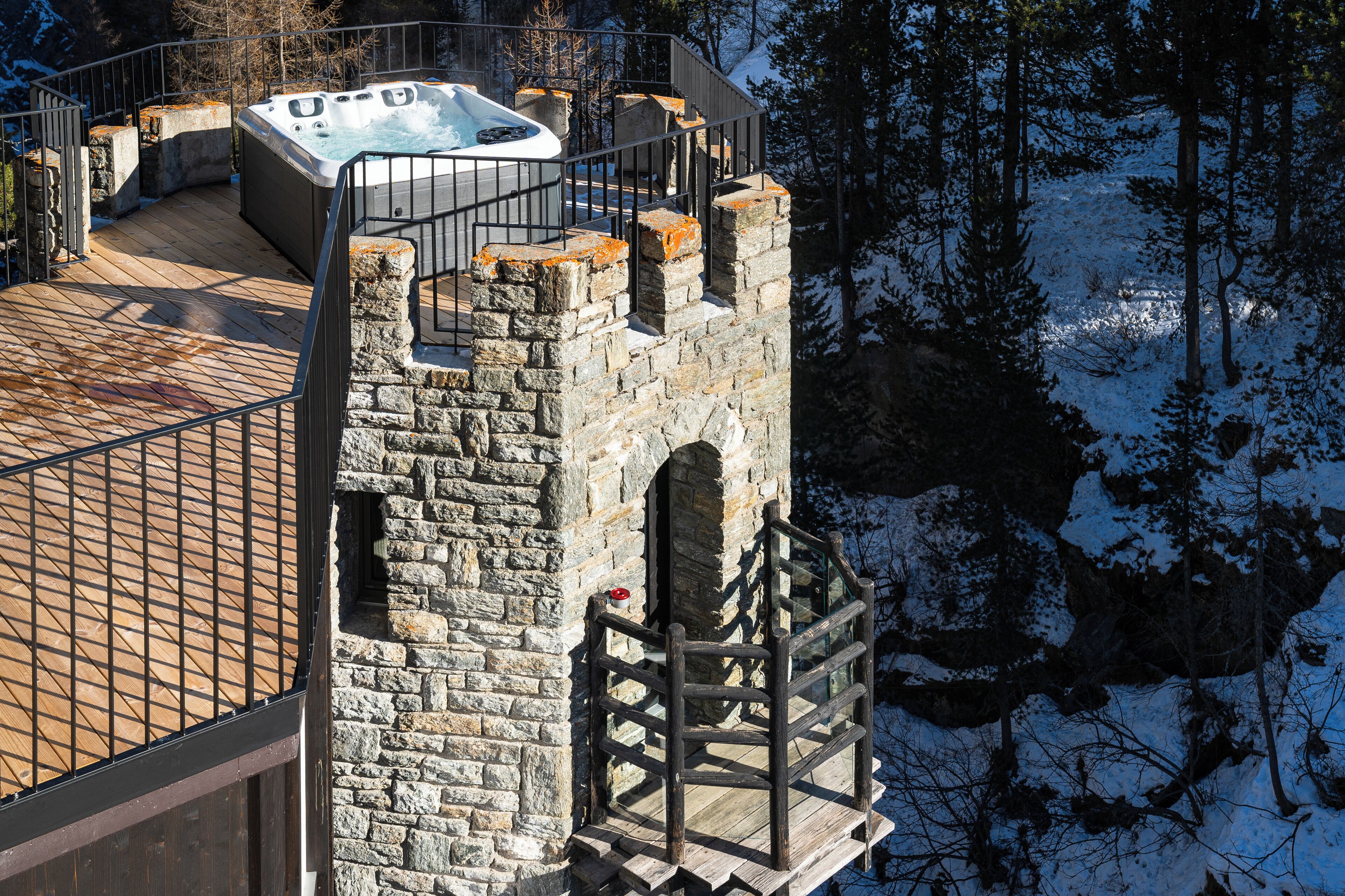 Une tour en pierre dotée d’une terrasse en bois et d’un jacuzzi.